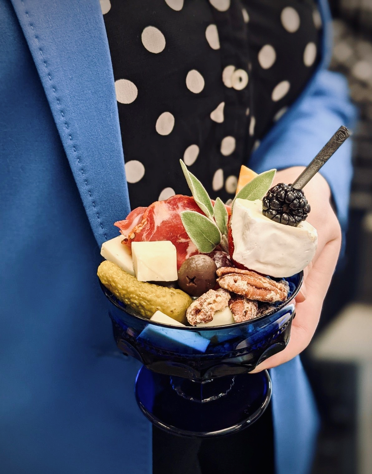 Person holding glass of charcuterie items